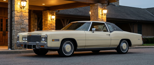 Cream 1975 Cadillac Eldorado two-door coupe under a country club portico at dusk