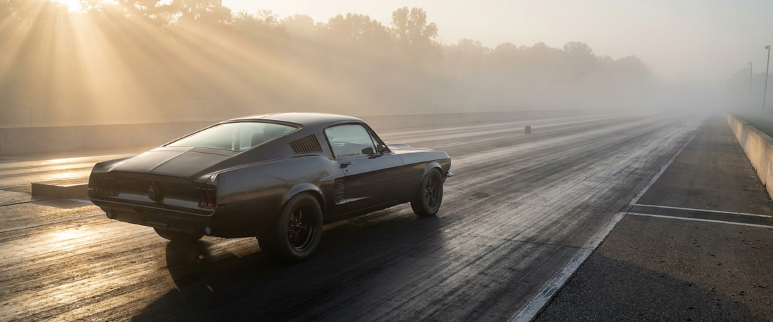 Late 1960s American muscle car on a misty drag strip at dawn