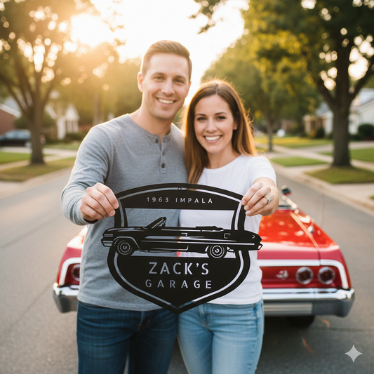 A smiling couple stands before a red 1963 Chevy Impala convertible, proudly holding a custom garage sign that reads "1963 Impala Zack's Garage" on a quiet suburban street.