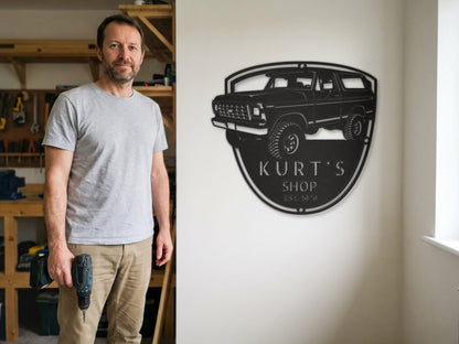 Owner in his shop after hanging a personalized 1978 Ford Bronco garage sign in black steel