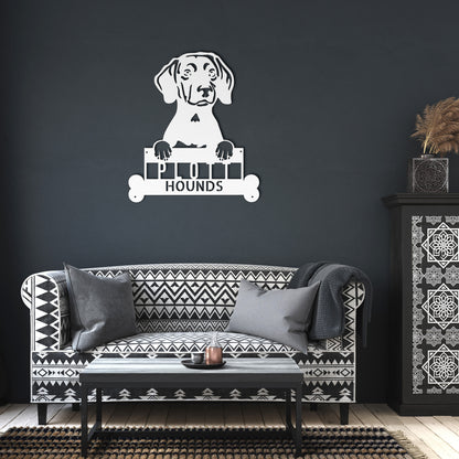 A brick house entrance with a wooden front door, a potted plant with white flowers, and a PITBULL METAL SIGN ARTWORK, Custom Plott Hound Home Décor, Personalized Dog Name Sign, Gift for Animal Enthusiasts featuring a dog's head and the word "HOUNDS" below it.