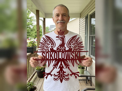 Man holding a red personalized Polish eagle name sign reading SOKOLOWSKI on his front porch