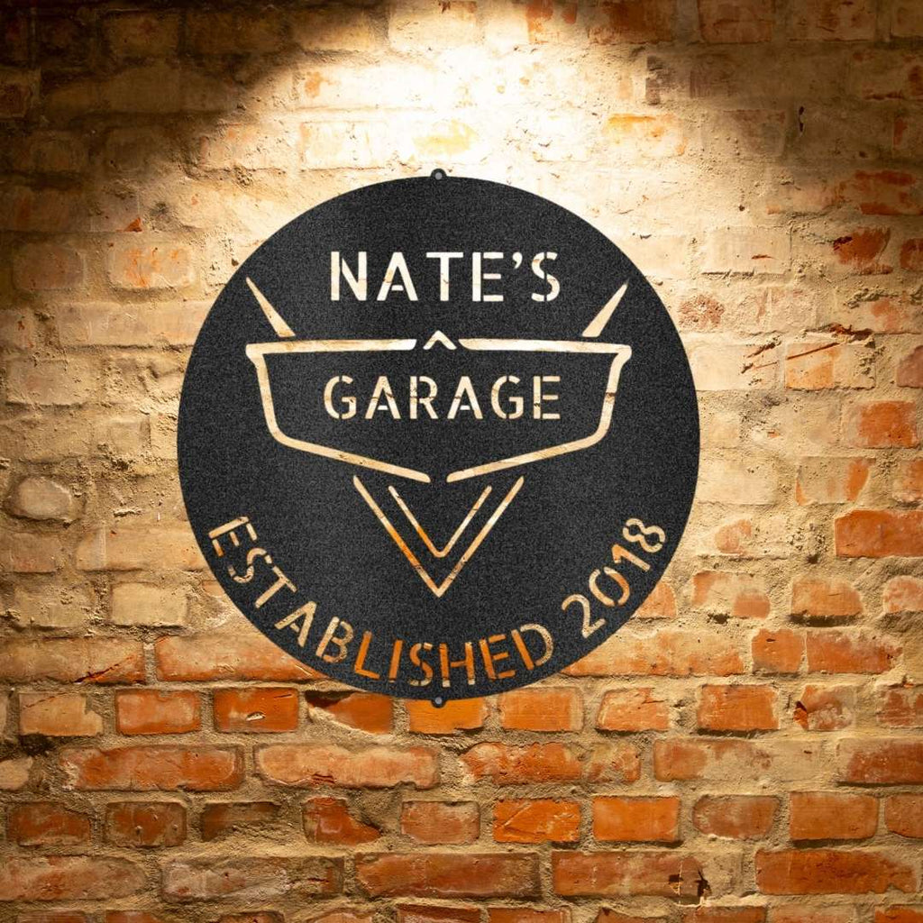 A PERSONALIZED Steel Monogram Garage Decor - Metal Wall Art that says nate's garage established 2018 on a brick wall.