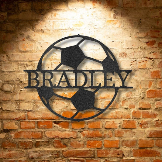 A durable soccer monogram metal sign with the name Bradley on a brick wall.