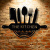 The Kitchen Monogram - Steel Sign logo on a brick wall, showcasing personalized steel monogram and unique metal art gifts.