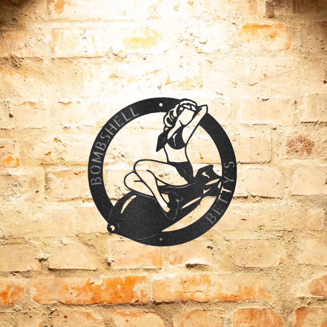 A unique metal art gift featuring a durable outdoor metal sign of a woman riding a bike on a brick wall.