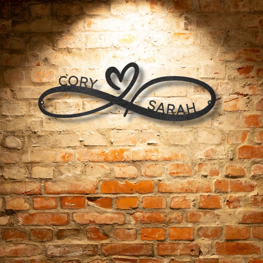 A personalized steel monogram featuring the names cory and sarah, hanging on a brick wall.