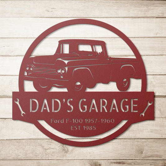 A steel monogram sign, personalized with an outline of a Ford F-100 truck and the text "Dad's Garage, Ford F-100 1957-1960, EST 1985" against a wooden-style background, makes an ideal addition to home decor.