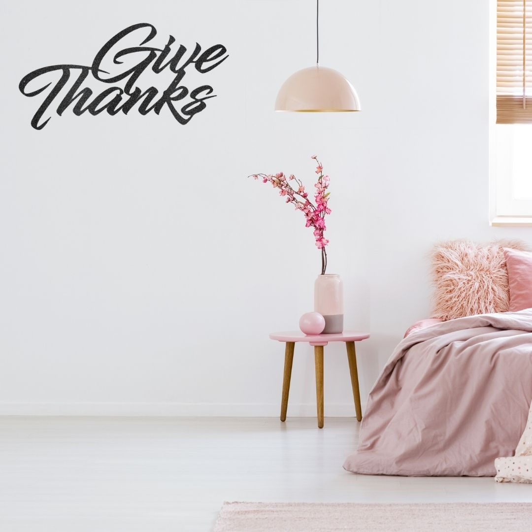 A durable metal sign displaying "Give Thanks" on a brick wall, perfect for outdoor decor.