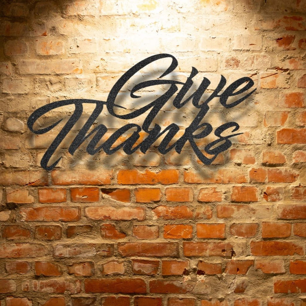 A durable metal sign displaying "Give Thanks" on a brick wall, perfect for outdoor decor.