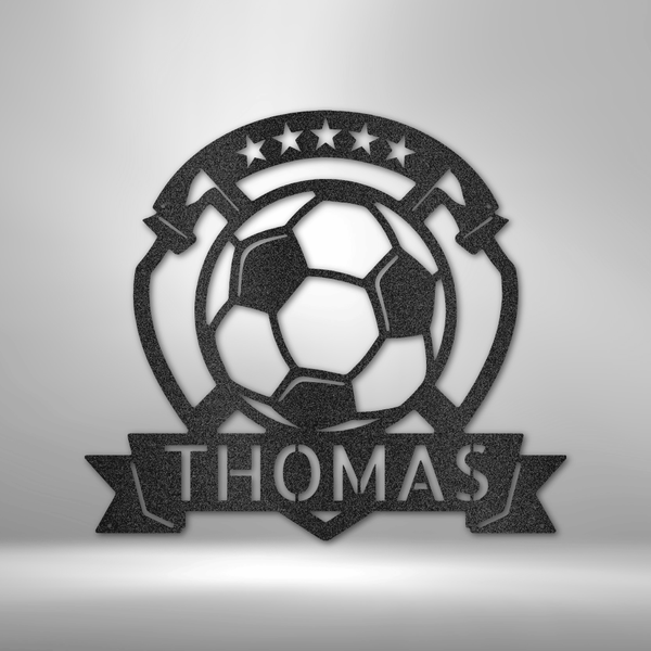 A personalized steel monogram of the name Thomas, displayed as a soccer plaque, adorning a brick wall.