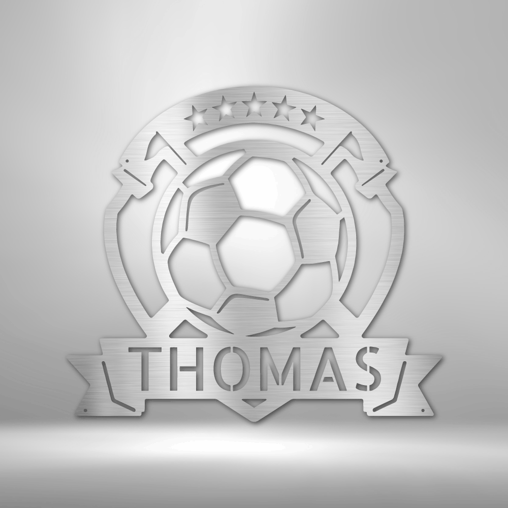 A personalized steel monogram of the name Thomas, displayed as a soccer plaque, adorning a brick wall.