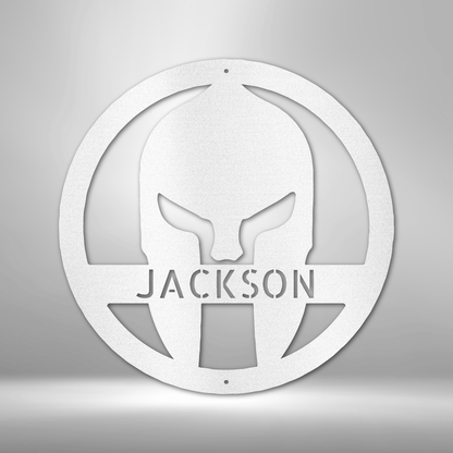 A Durable Outdoor Metal Sign featuring a Custom Handmade Design of a Spartan Helmet with the name Jackson on a brick wall.