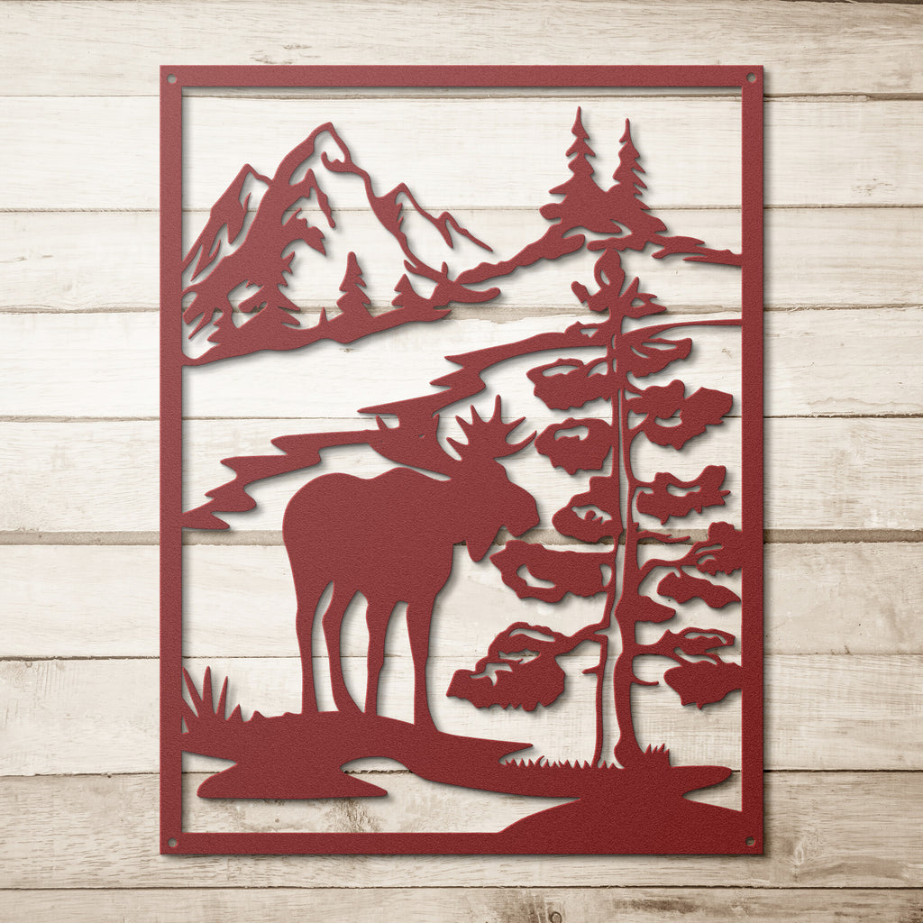 A Custom Handmade Steel Monogram of a Moose in the Snow, serving as a Unique Metal Art Gift and above the bed wall decor, set amidst trees and mountains in the woods.