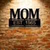 A UNIQUE Metal Wall Art Decor - Personalized Mother's Day Plaque with the word mom, hanging on a brick wall.