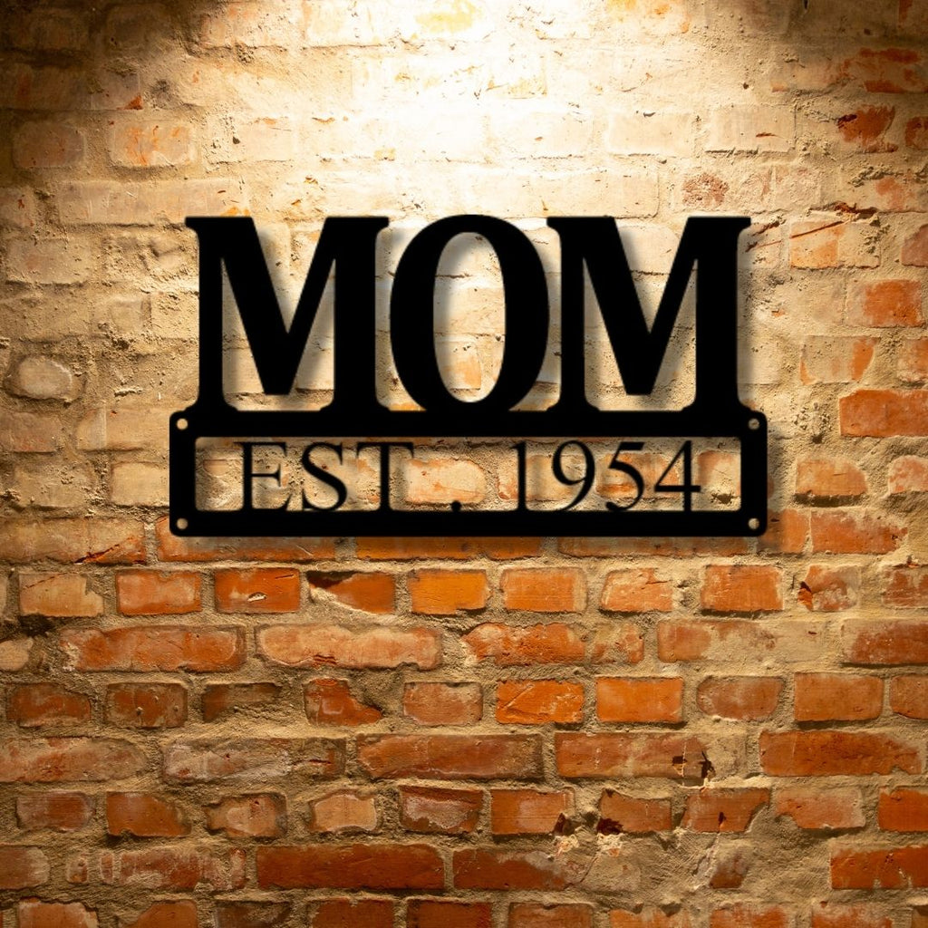 A PERSONALIZED Mother's Day Plaque - Unique Metal Art Gift that says mom est 1954 hanging on a brick wall.