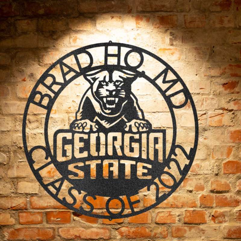 The personalized Georgia State Monogram 2 logo is a durable, custom handmade steel sign displayed on a brick wall.